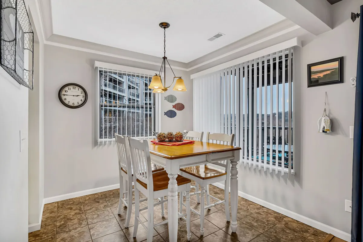 A warm, inviting dining area with a table set near a window, through which you glimpse a gentle exterior view. Sunlight bathes the interior, enhancing the cozy, modern décor and suggesting an ideal spot for intimate breakfasts or evening wine.