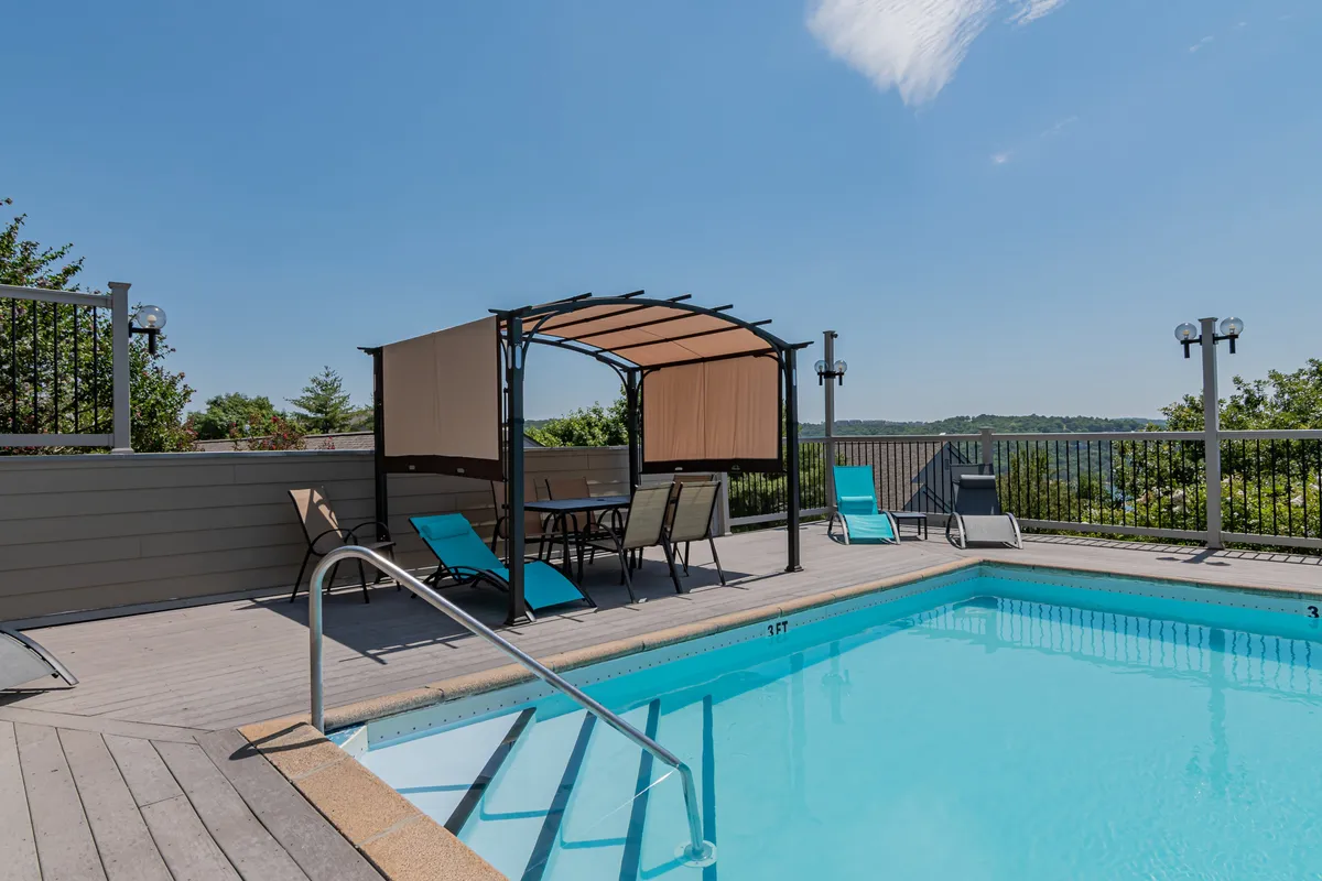 An inviting outdoor swimming pool area featuring lounge chairs, a shaded canopy, and surrounding greenery. The pool exudes a relaxed, family-friendly vibe, ideal for swimming, sunbathing, and social gatherings after a day of adventure.