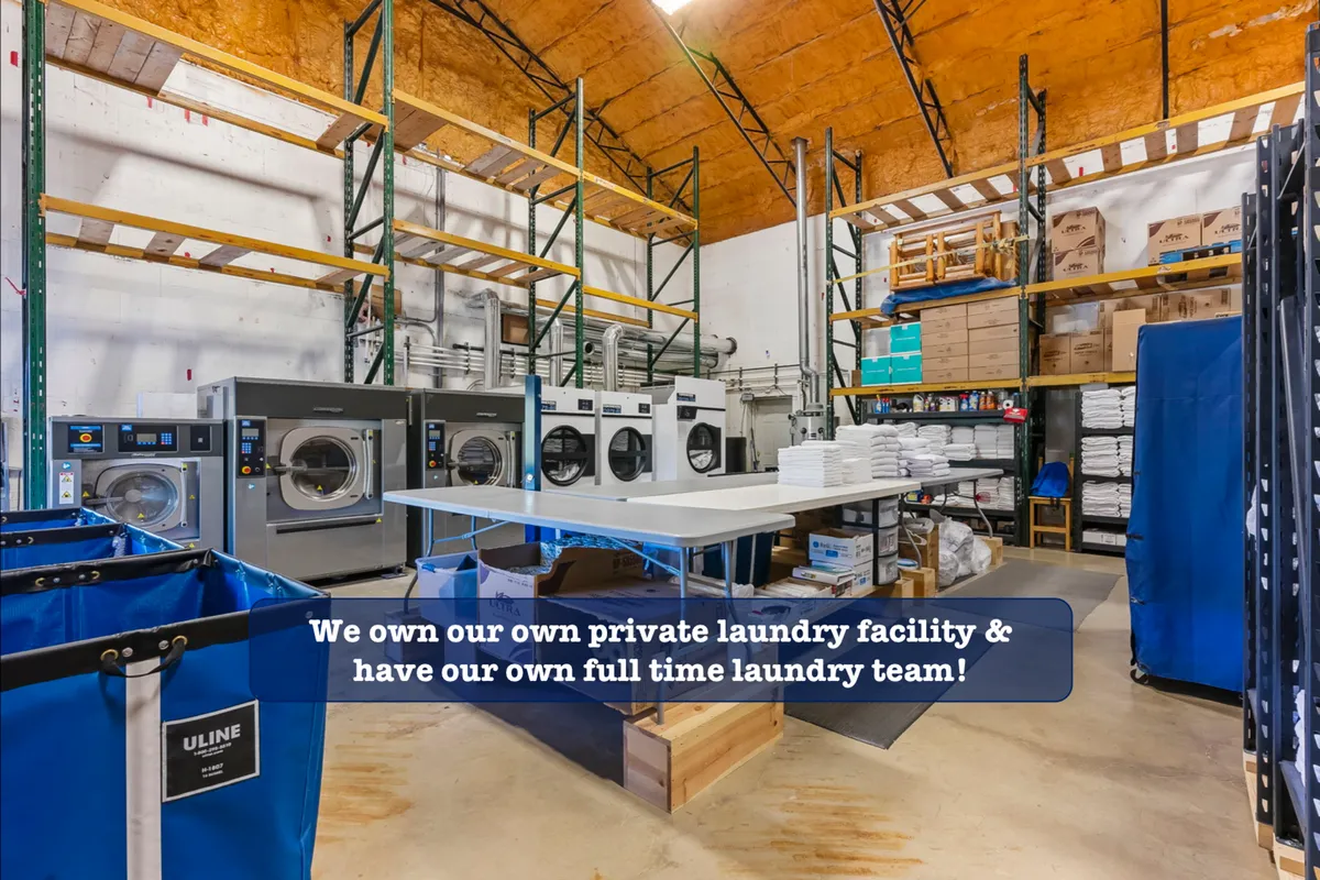 A row of industrial washing machines and laundry folding tables set in a clean, efficient space. The image conveys the meticulous standards behind the condo’s commercial-grade cleaning guarantee.